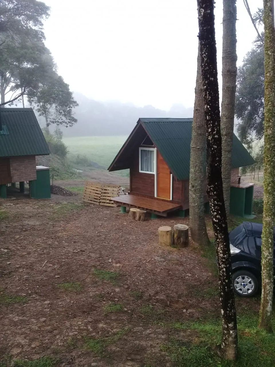 Chalés na neblina de uma manhã fria, com os campos e as montanhas encobertos