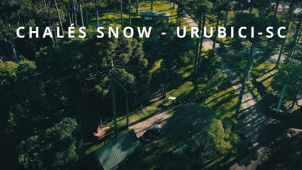Vista aérea dos chalés de telhado verde entre araucárias, com o título Chalés Snow – Urubici-SC